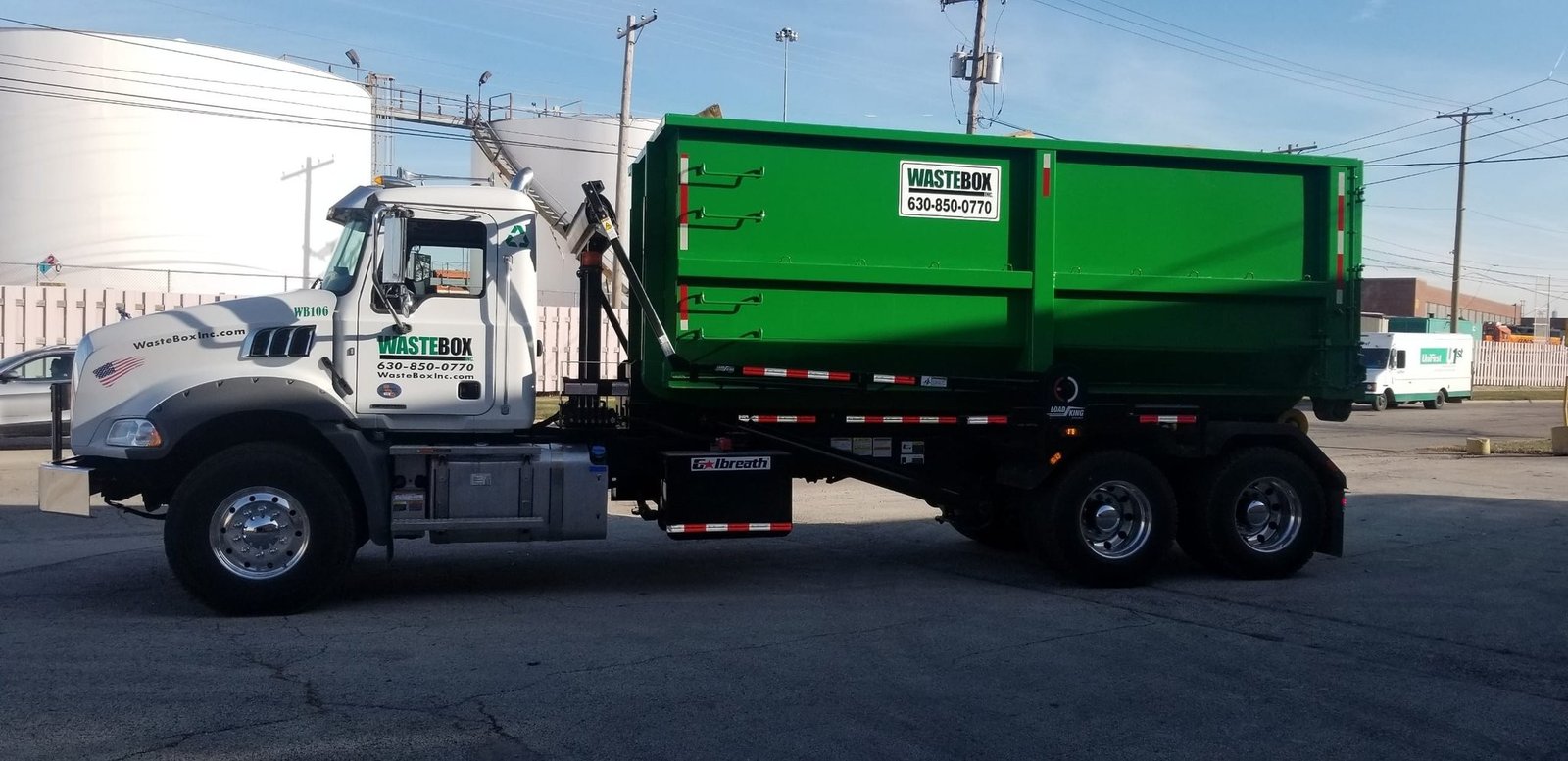 WasteBox roll-off truck WB106 carrying a green container at the Lemont yard